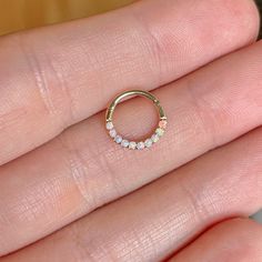 a woman's hand holding a gold ring with small white stones on the inside