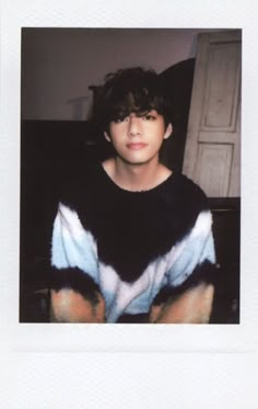 a young man sitting on top of a couch wearing a sweater