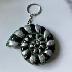 a green and silver flower shaped keychain sitting on top of a white table