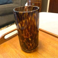 a brown glass sitting on top of a wooden table next to a gray couch in a living room