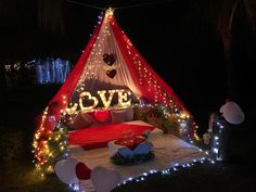 a bed covered in lights and pillows under a red tent with love written on it