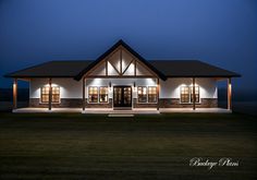 a large house lit up at night with lights on the front porch and side windows