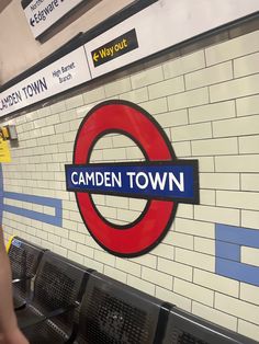 there is a sign that says camden town on the wall next to benches in an underground station