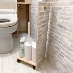 a bathroom with a toilet, sink and brick wall