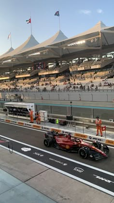 two racing cars are on the track in front of an audience at a sporting event