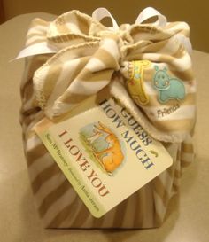 a baby shower gift wrapped in brown and white striped paper with a tag on it