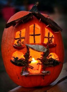 a carved pumpkin with a house made out of it's windows and plants inside