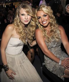 two beautiful young women sitting next to each other in front of a crowd at a party