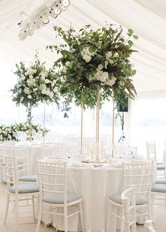 the tables are set up with white linens and flowers in tall centerpieces