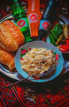 an assortment of food on a plate with bread and beer bottles in the back ground