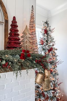 a fireplace decorated with christmas trees and other holiday decorations, including red bells on the mantel