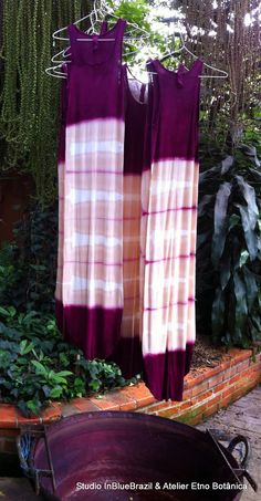 two purple and white dresses hanging on clothesline in front of brick wall with potted plants