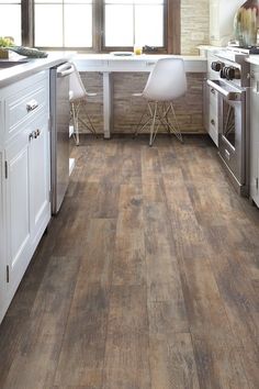 an image of a kitchen setting with wood flooring and white cabinets on the walls