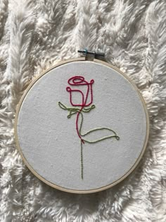 a red rose embroideryed onto a white piece of fabric on a furry surface,