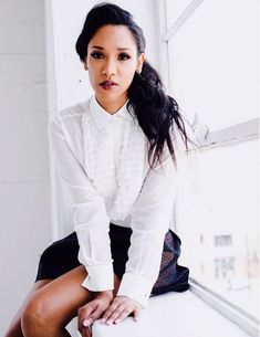 a woman sitting on top of a window sill wearing a white shirt and black skirt