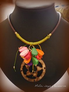 the necklace is decorated with colorful flowers on it's own neckline and has a wooden bead