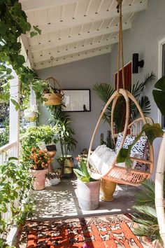 a porch with potted plants and hanging chairs