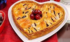 a heart shaped cake on a plate with cherries