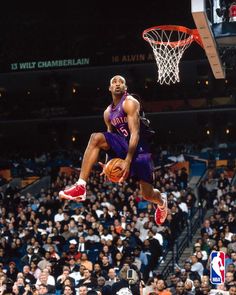 a basketball player jumping up into the air to dunk a ball in front of an audience