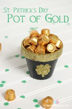 a cup filled with gold coins on top of a white table next to shamrocks