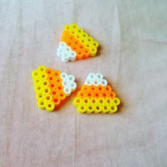 three lego pieces are laying on the table together, one is yellow and one is white