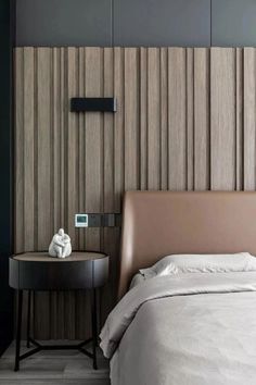 a bedroom with a bed, night stand and wooden paneling on the wall behind it