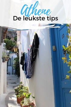 an alleyway with clothes hanging on the wall and potted plants in pots next to it