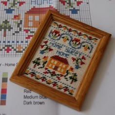 a cross stitch pattern in a wooden frame on top of some other cross - stitch patterns