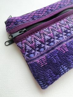 a close up of a zippered pouch on a white surface with purple and blue designs