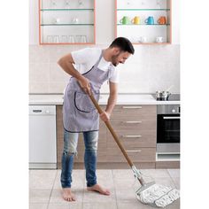 a man cleaning the floor with a mop in his hand and wearing an apron