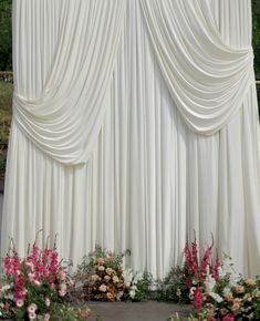 an outdoor ceremony with white drapes and flowers