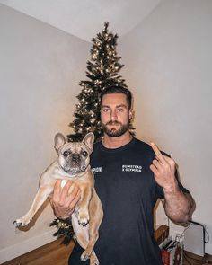 a man holding a dog in front of a christmas tree