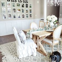 a dog is standing in front of a dining room table with chairs and pictures on the wall