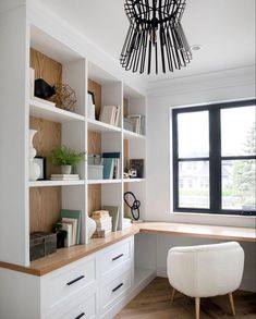 an office with white bookcases and wooden flooring next to a large window