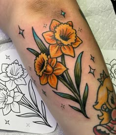 a woman's leg with yellow flowers and stars on the side, next to her tattoo