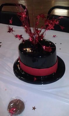 a black and red cake on a table with silver stars around it, in front of a dime