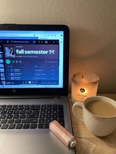 an open laptop computer sitting on top of a desk next to a cup of coffee