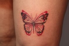 a close up of a butterfly tattoo on someone's leg with red and black ink