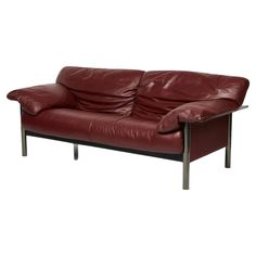 a red leather loveseat with metal legs and arm rests on a white background