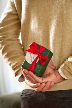 a man holding a green gift box with a red bow on it's ribbon