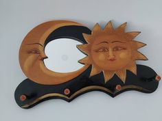 a decorative sun and moon face on a black, gold and white wall mounted mirror