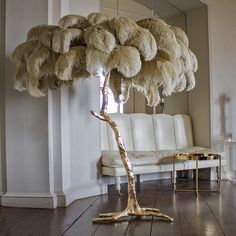 an ostrich tree in the middle of a living room with white chairs and chandelier