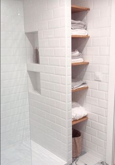 a white tiled shower with shelves in it