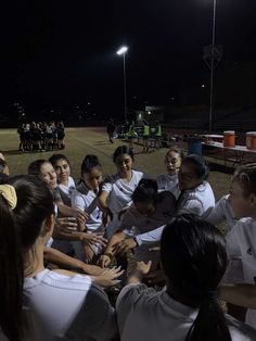 a group of young women standing around each other on top of a field at night