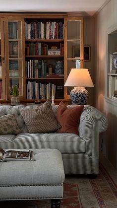 a living room filled with furniture and bookshelves next to a lamp on top of a table