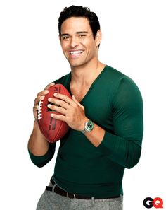 a black and white photo of a man with a football in his hand, smiling at the camera