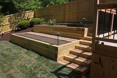 a wooden deck in the middle of a yard with steps leading up to an open door