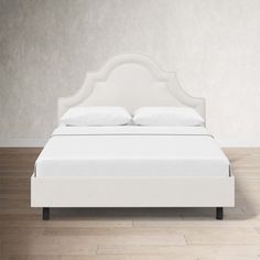 a white bed sitting on top of a wooden floor