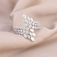 a close up view of a ring on a pink cloth with white stones in the middle