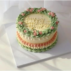 there is a cake decorated with flowers and leaves on the top layer that says happy birthday